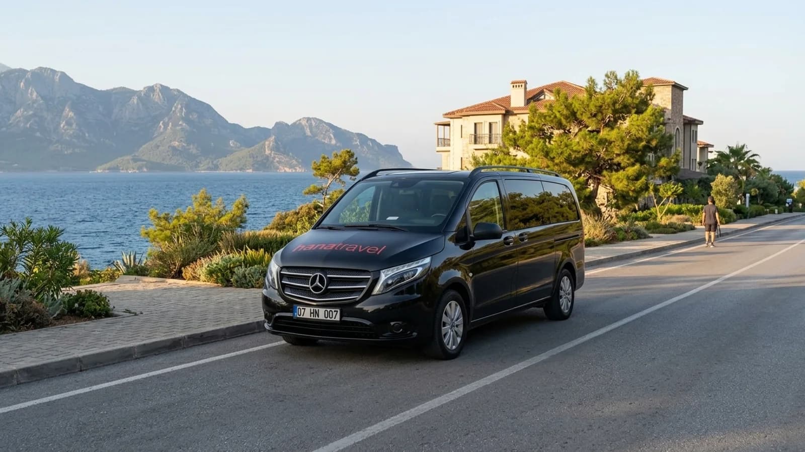 How Your Kemer Private Taxi Transfer Works Step by Step A black transfer van parked on a scenic coastal road overlooking the Mediterranean Sea near Antalya.